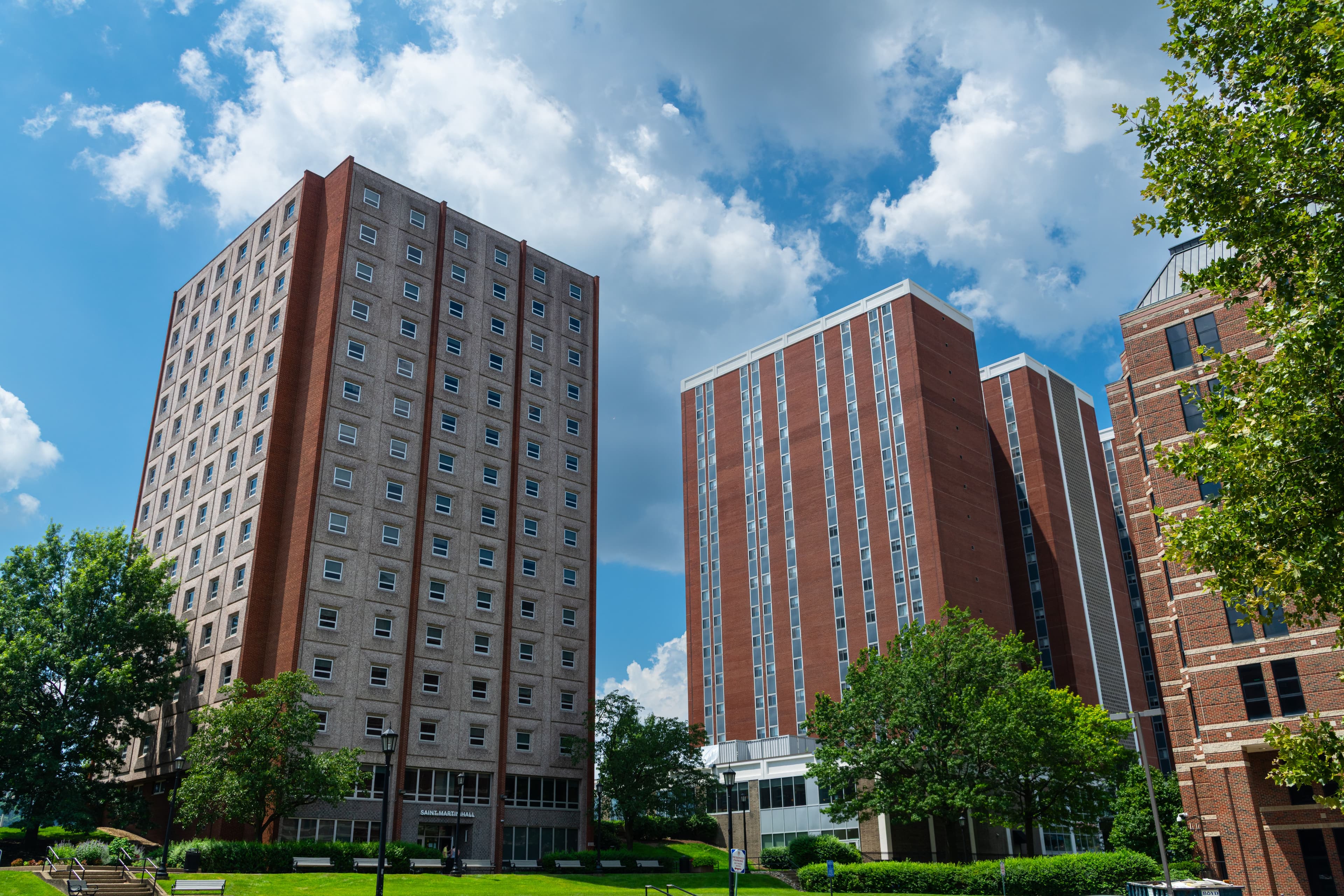 Twin residence hall towers on a college campus under a blue sky
