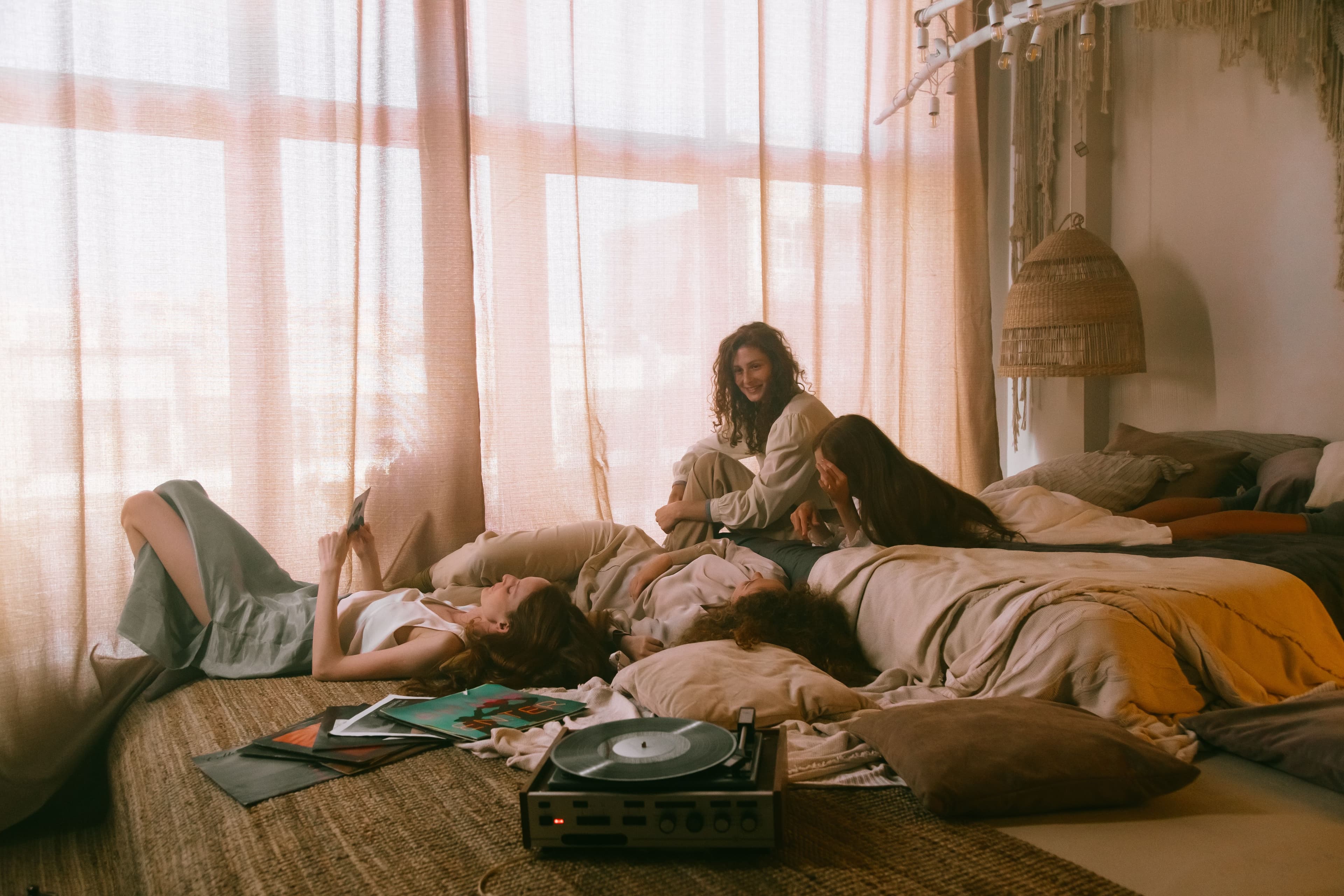 Friends relaxing together on a bed in a sunlit room with a record player
