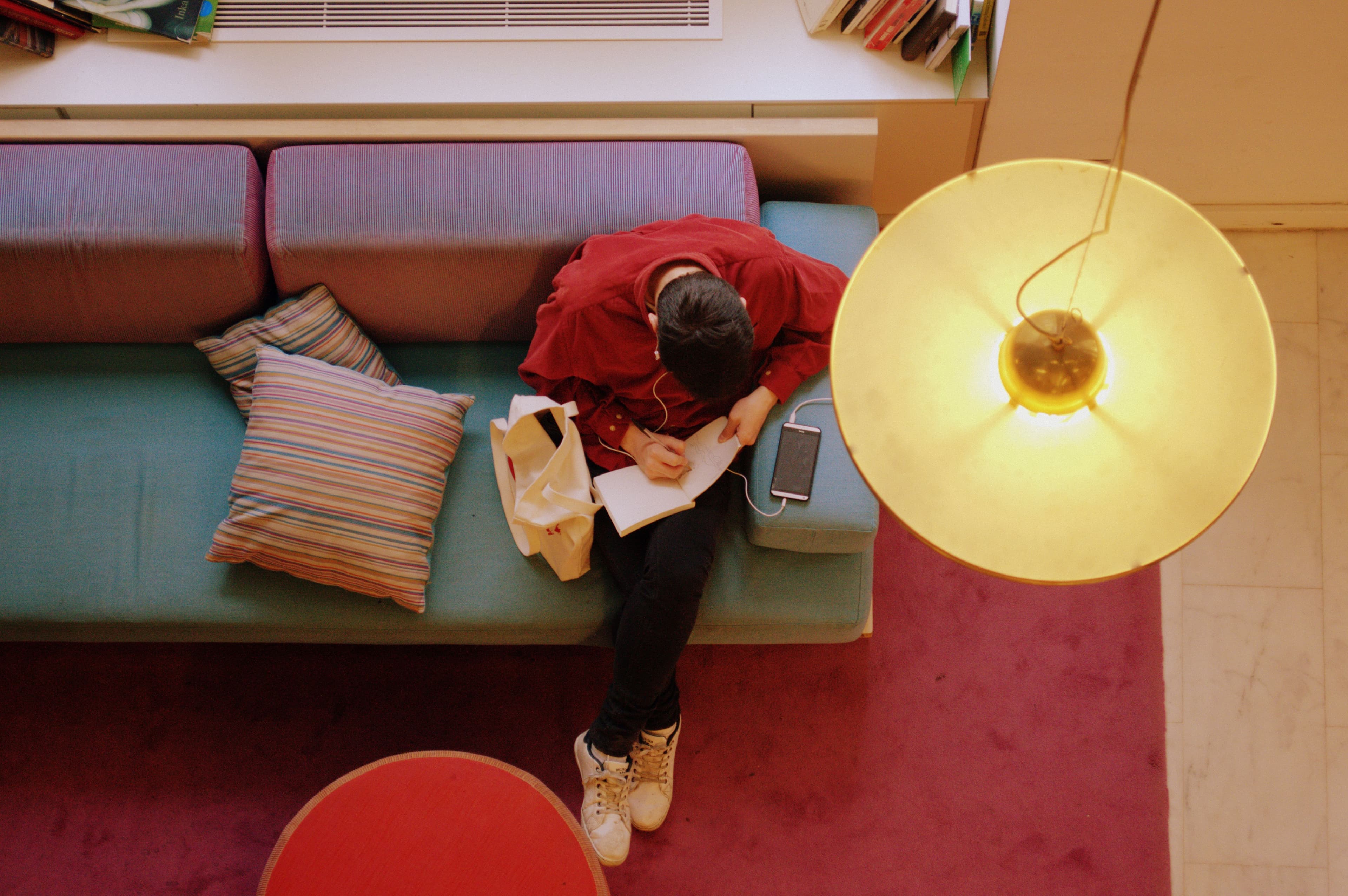 Overhead view of a student writing in a notebook on a couch