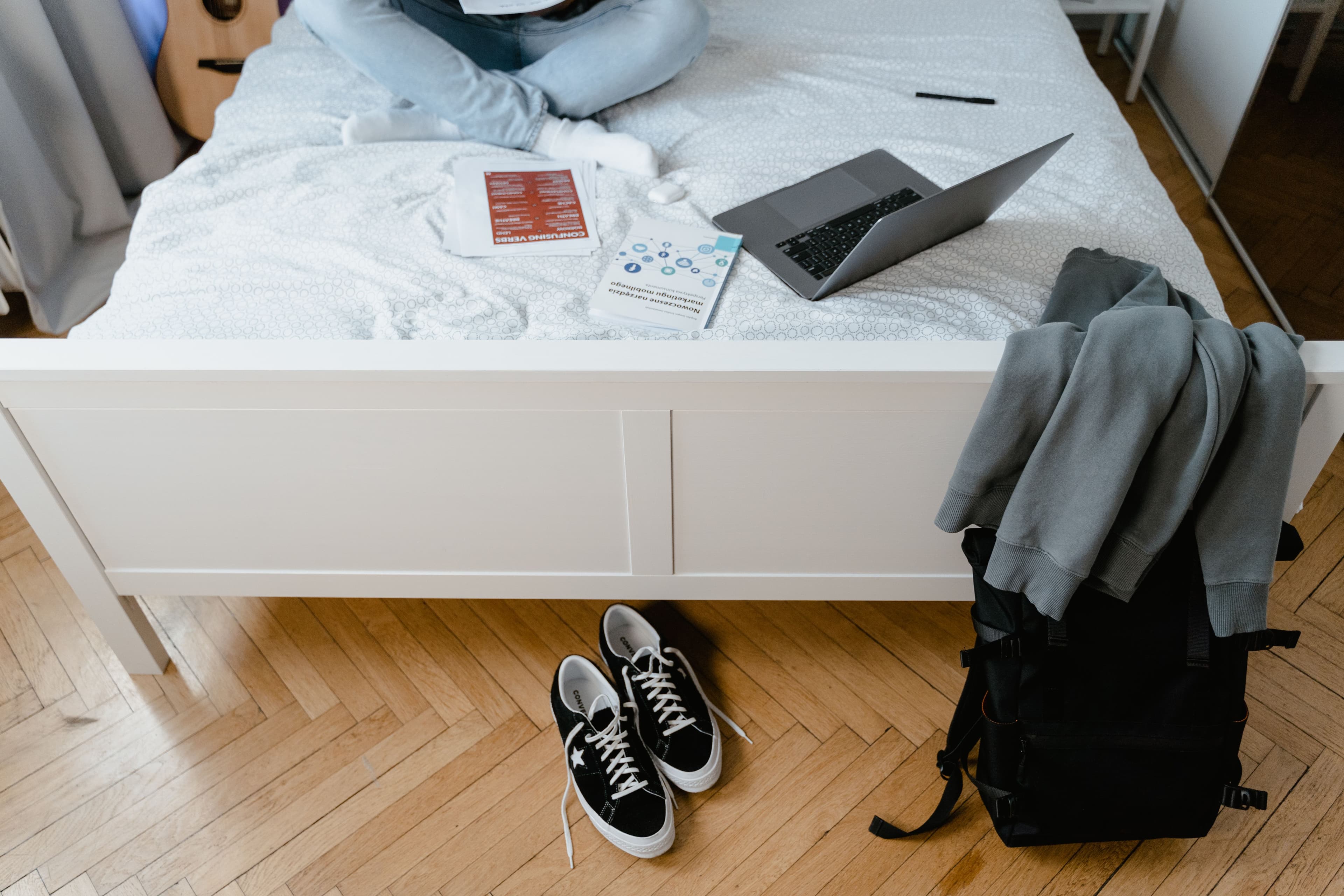 Modern apartment bedroom with a made bed and sneakers on the floor